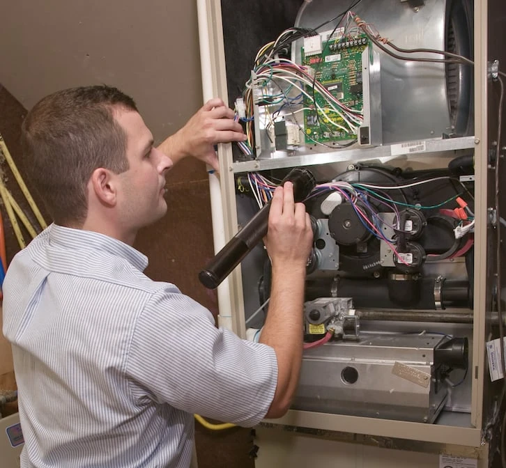 An HVAC service professional inspecting a furnace in need of heating repairs in McKinney, TX.