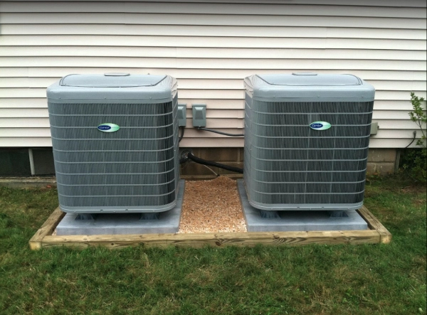 Two outdoor air conditioning units sitting side-by-side after being worked on by an HVAC service professional.