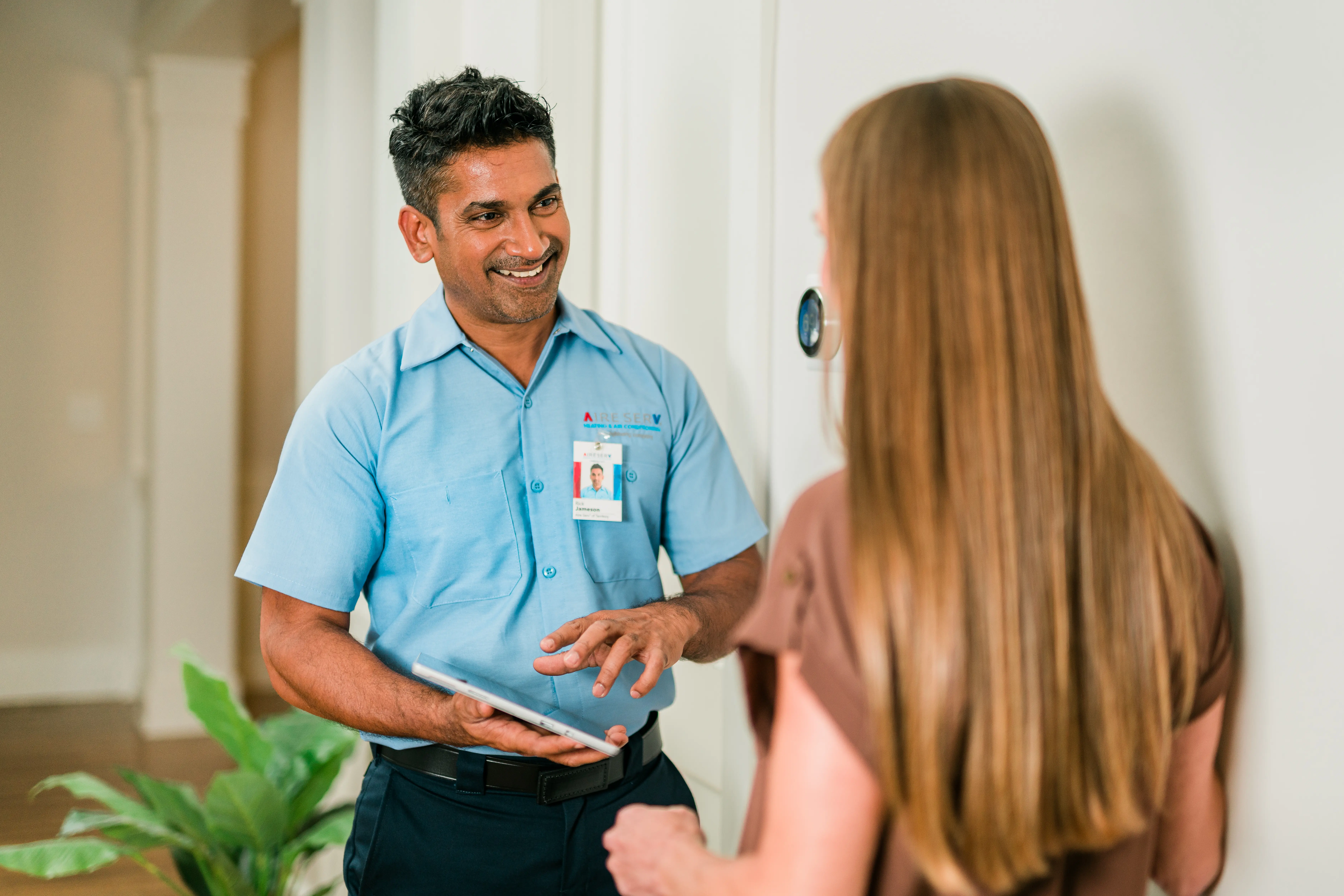 AireServ representative speaking with a customer while holding a clipboard.