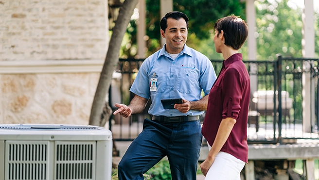 Aire Serv professional talking with a customer by an outdoor AC unit.