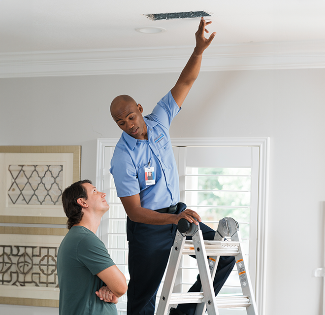 Aire Serv technician showing a customer an air vent in their ceiling.