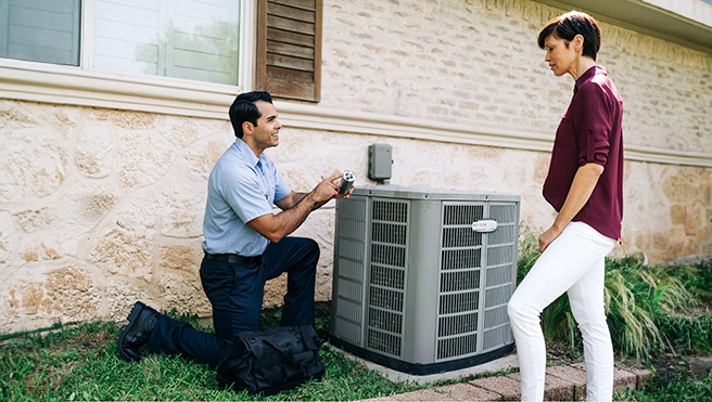 An Aire Serv technician talks with a customer by their air conditioning unit outside.