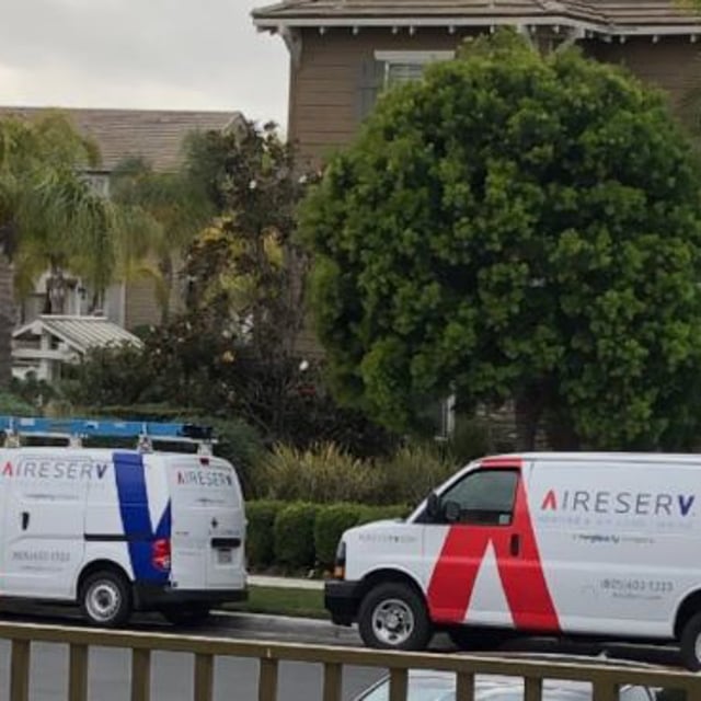 2 Aire Serv Vans parked outside of homes.