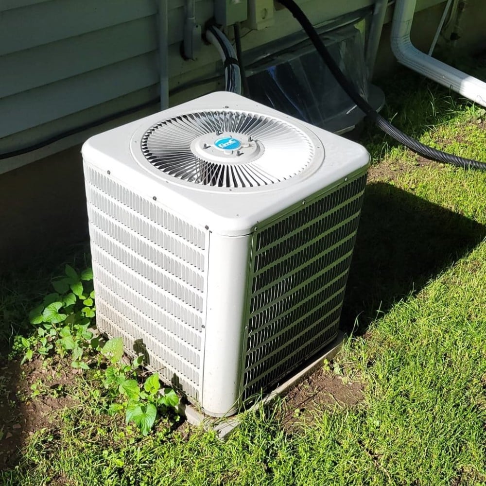 White AC Unit in a Yard Surrounded by Grass