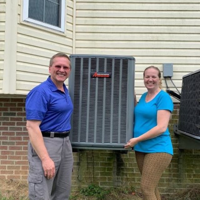 Aire Serv owner with customer in front of new Amana AC condenser outside of cream colored home.