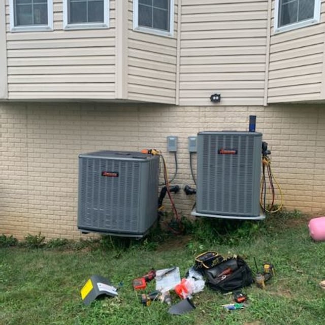 Amana AC units outside of tan brick home with HVAC tools in hard.