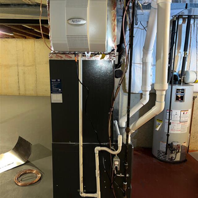 Black and grey HVAC unit with white pipes