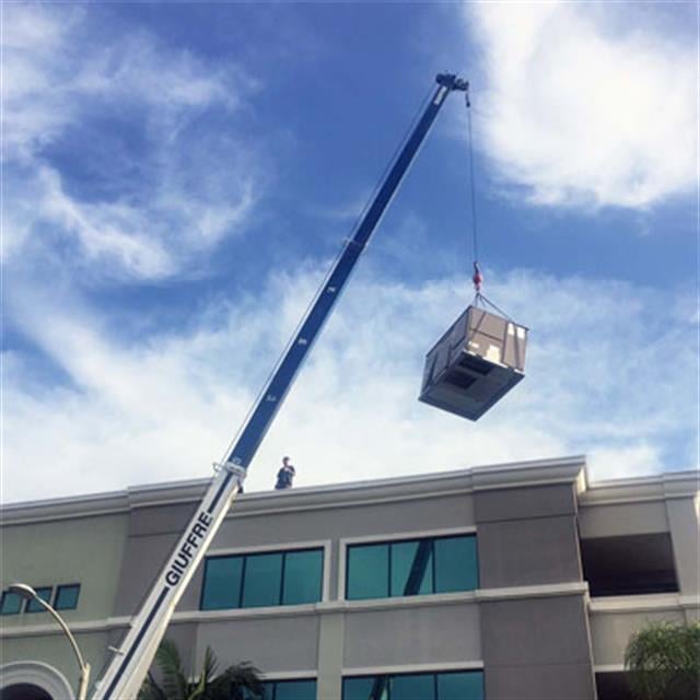 Boom truck crane lifting AC unit onto roof