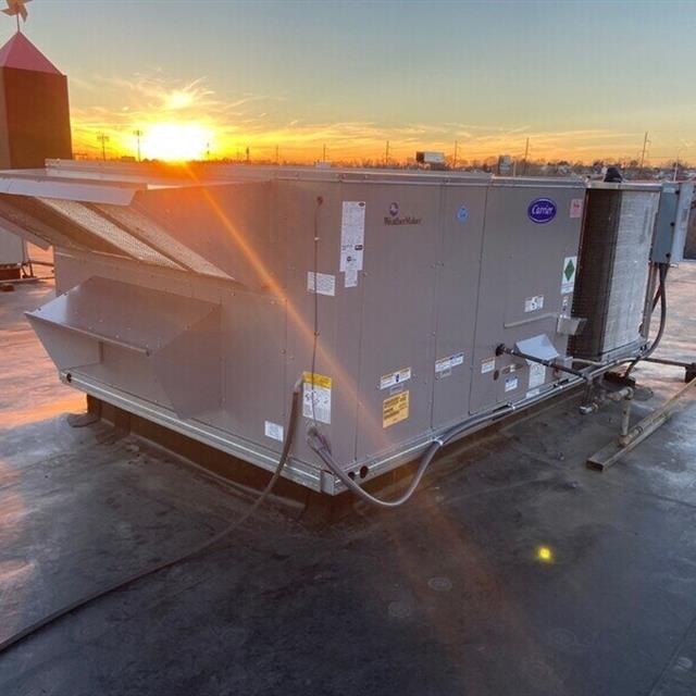 Commercial roof HVAC unit in front of a sunset