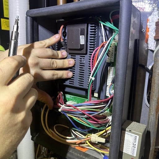 Empolyees hands working on repairing a boiler with multiple colored wires