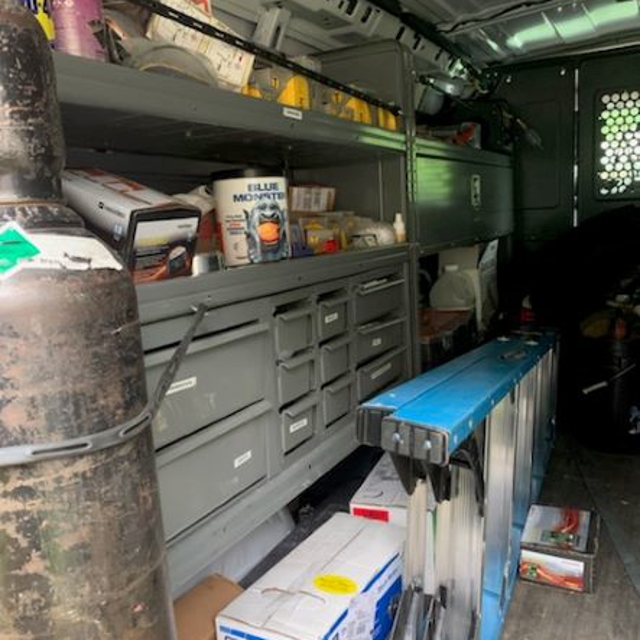 Inside the back of an Aire Serv van with ladder and tool chest.