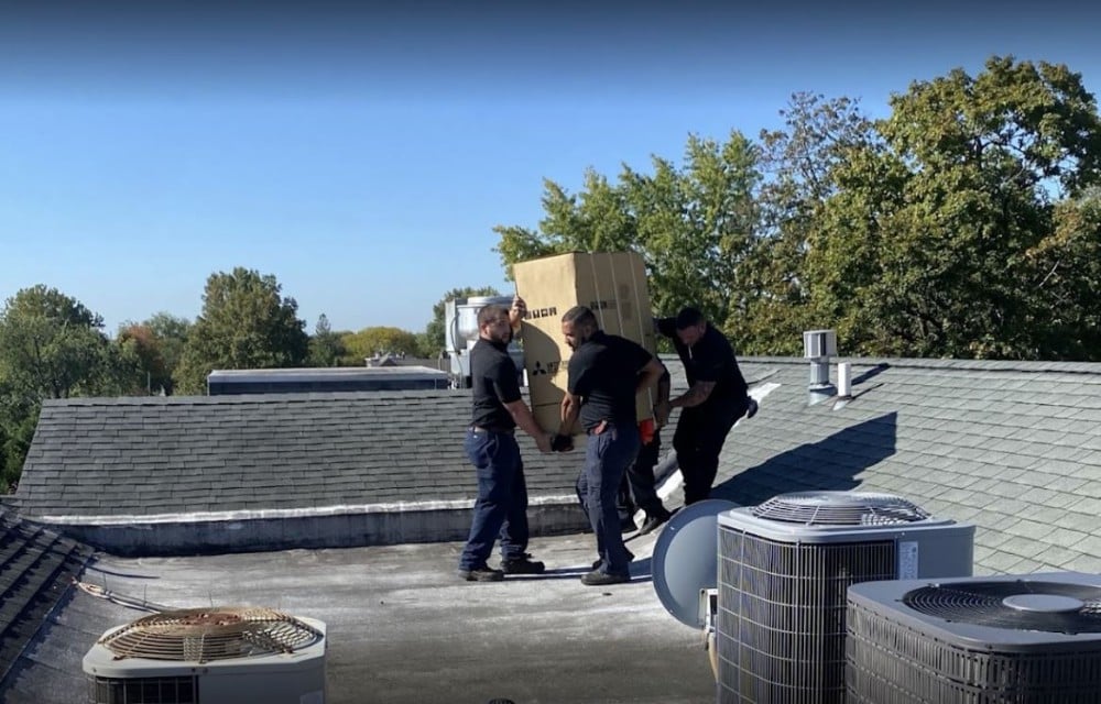 Three Aire Serv technicians replacing a rooftop ac system.