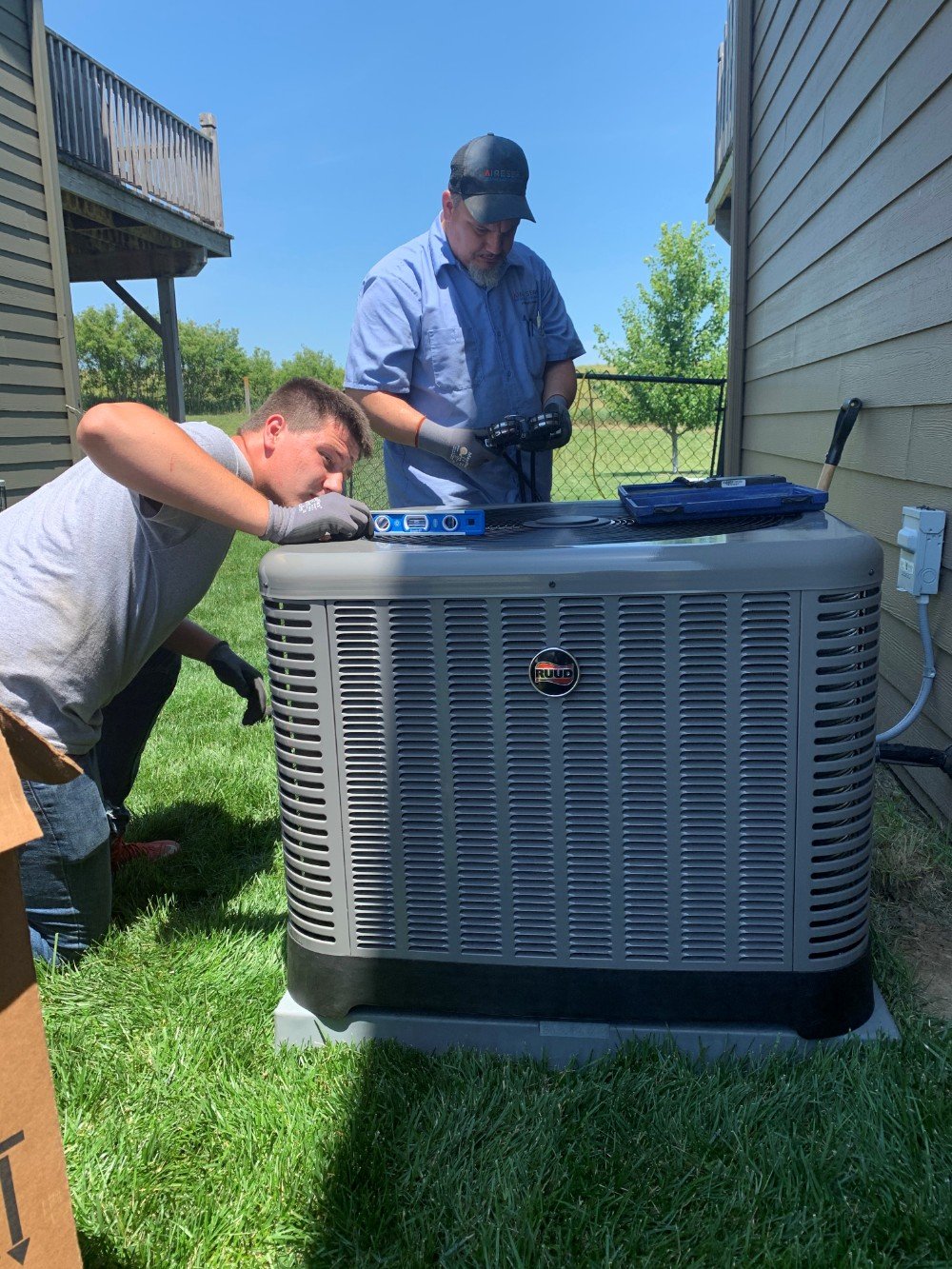 Technicians checking the systems on a new air conditioning unit outside.