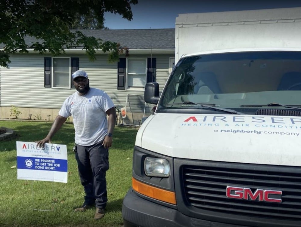 Aire Serv of Metairie technician at the job in front of his van, putting up the sign about the promise to get the job done right.