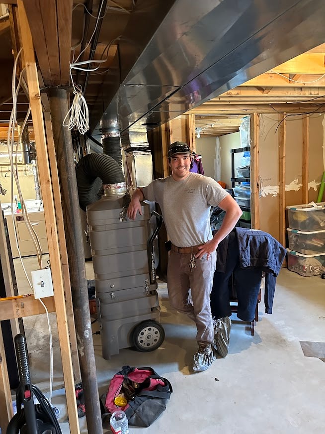 Our technician Chris smiling while working on cleaning out air ducts in a home.