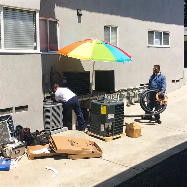 Two technicians working outside under beach umbrella