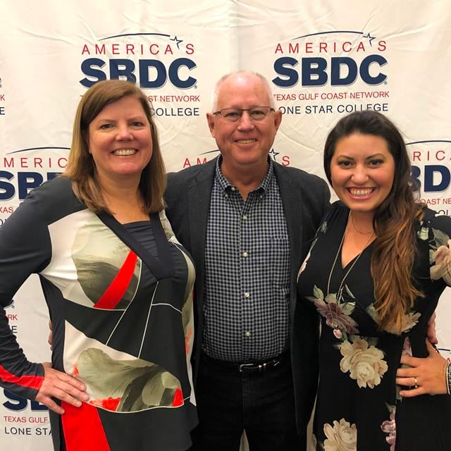 a man with two women in front of SBDC banner