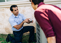 An Aire Serv professional working on an air conditioning unit outside.