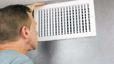 Person assessing ceiling duct vent