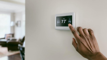 Hand reaching toward touch screen thermostat.