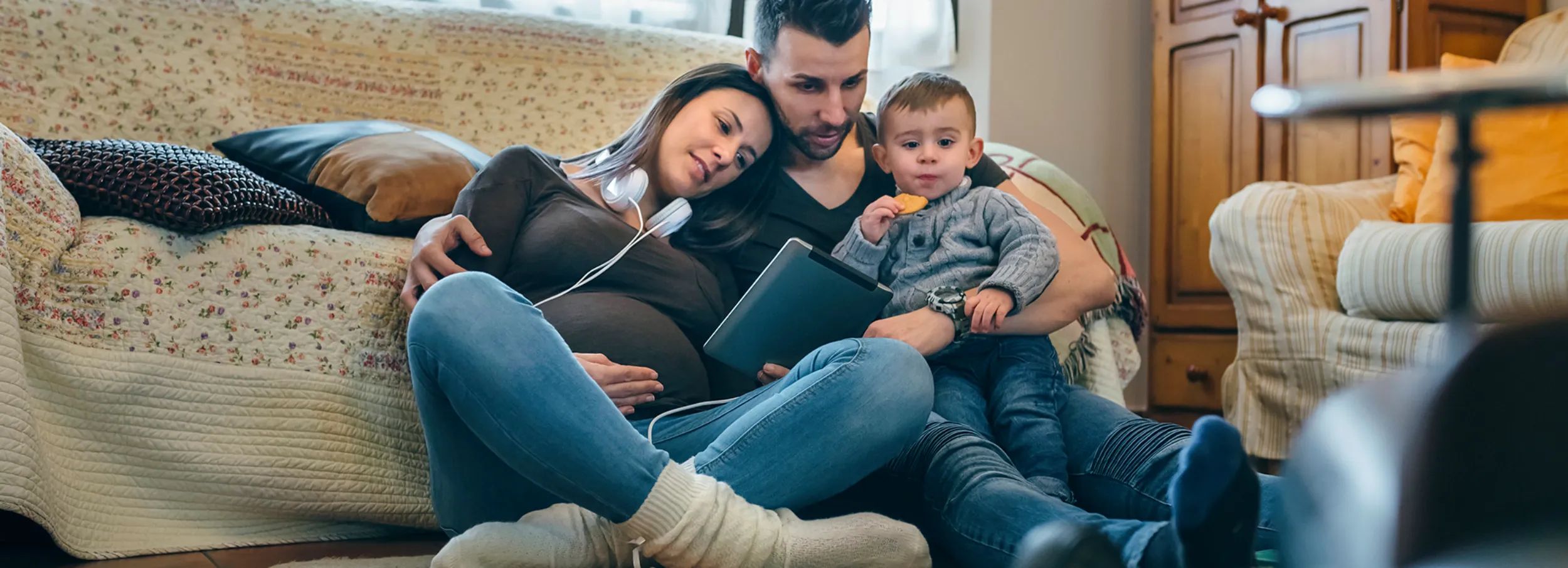 A pregnant mom, son and dad viewing a tablet.