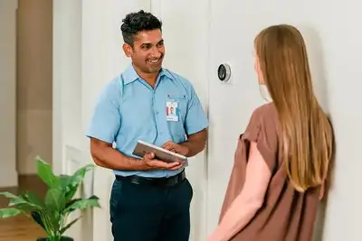 An Aire Serv emergency technician talking to a customer inside her house.