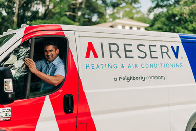 A Aire Serv 24/7 technician smiling while driving his service van