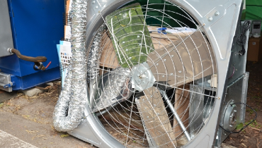 Large attic fan in steel casing ready for installation in residential home.